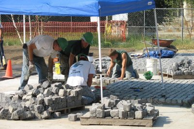 Masons setting cobblestones at the Alumni Walk entrance. (Doug Hubley/Bates College)