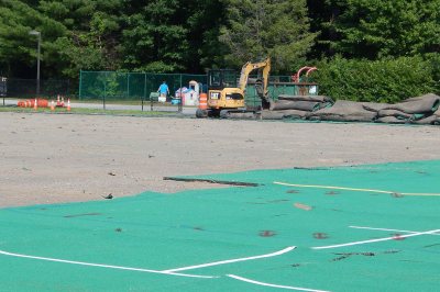 With some of the AstroTurf still in place on Campus Avenue Field, an excavator stacks rolls of the turf that have just been peeled off on July 6, 2016. (Doug Hubley/Bates College) 