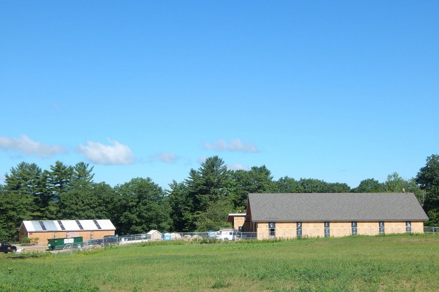 The 1988 Bates boathouse, at left, and the new facility, pictured on July 11, 2016. The Androscoggin River is behind the trees. (Doug Hubley/Bates College)