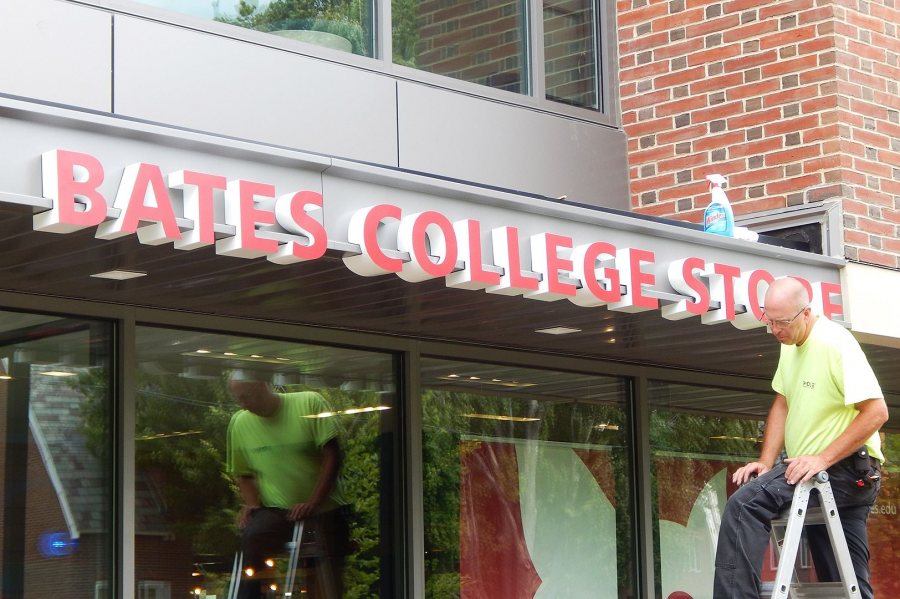 A technician for Exposé Signs & Graphics has just finished mounting a sign for the College Store on a front canopy at 65 Campus Ave. (Doug Hubley/Bates College)