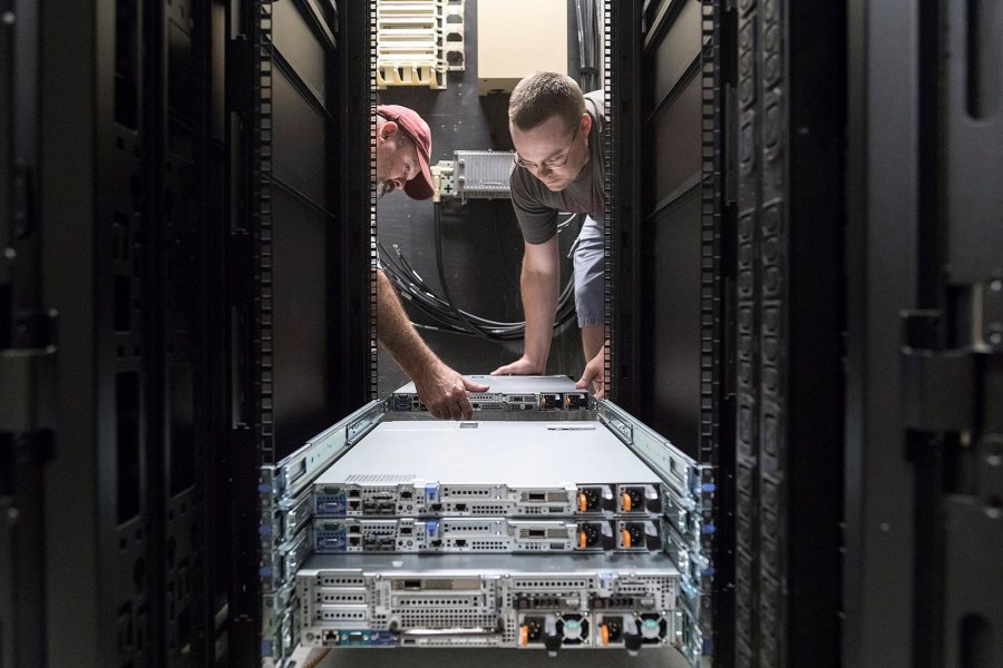 Network Infrastructure Project Manager Kevin Poland, left, and Desktop Operations Analyst Matthew Thomas install components of Bates' new High Performance Computing Cluster at 65 Campus Ave. New members of the physics faculty have taken the lead in bringing the system to Bates. (Josh Kuckens/Bates College)