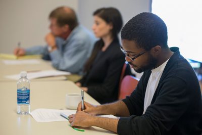 Jeremy Glover ’17 of Cleveland Heights, Ohio, takes notes during the New Approaches to Early Modern Literature and Culture symposium held at Bates on Sept. 26. In the background are Senior Lecturer in English Rob Farnsworth and Roya Biggie of Grinnell College. (Phyllis Graber Jensen/Bates College)