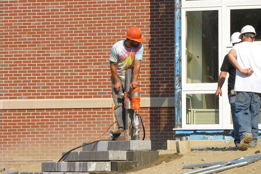 Taken for granite: A worker drills a hole in stone steps for a handrail at the new student housing. (Doug Hubley/Bates College)