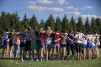 The women's ultimate team huddles for announcements at the beginning of practice on the softball field. (Phyllis Graber Jensen/Bates College)