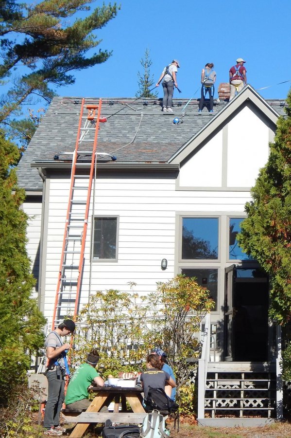 With student teams high and low, preparation for the installation of solar photovoltaic panels on Bates' Coastal Research Center, aka Shortridge, is underway late in the morning of Oct. 19, 2016. (Doug Hubley/Bates College) 