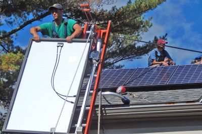 ReVision Energy's Ashton Ireland unloads a Canadian Solar PV panel from its sled. The modules weigh 44 pounds. (Doug Hubley/Bates College)