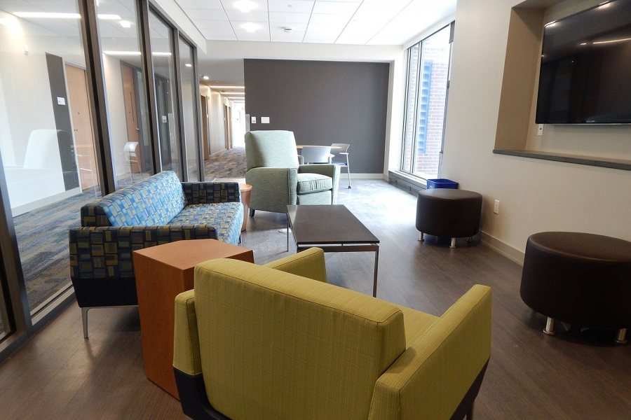 Taken in August shortly before students moved into Kalperis Hall, this lounge contains mixed furniture -- a table and chair at rear, and soft furniture for TV viewing. The glass walls afford "flow-by quality." (Doug Hubley/Bates College)