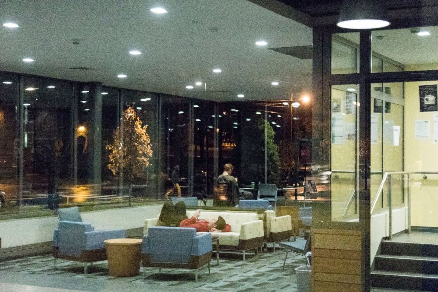 An evening scene in the lobby of Chu Hall is reflected in the building's storefront glass. A mix of furniture, an inventive floor plan, and an attractive fireplace around the corner make the lobby an attractive gathering spot. (Josh Kuckens/Bates College)