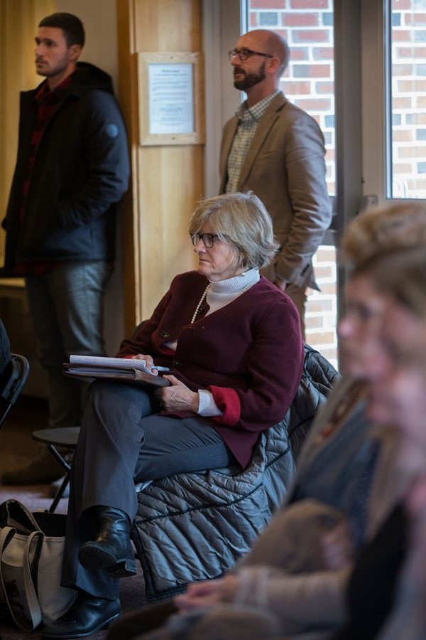 Bates President Clayton Spencer takes notes in the Mays Center during the "What Just Happened?" panel analyzing the 2016 election. Standing behind Spencer are Writing Specialist Chris Petrella, at left, and Dean of Students Josh McIntosh. (Phyllis Graber Jensen/Bates College)