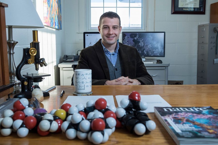 With a collection of model molecules in the foreground, Assistant Professor of Chemistry Andrew Kennedy is shown in his Dana Chemistry Hall office on Dec. 14, 2016. (Josh Kuckens/Bates College)