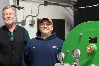 Bates energy manager John Rasmussen, at left, and boiler operator John Jasper pose by the new Renewable Fuel Oil burner on Jan. 19, 2017. (Doug Hubley/Bates College) 