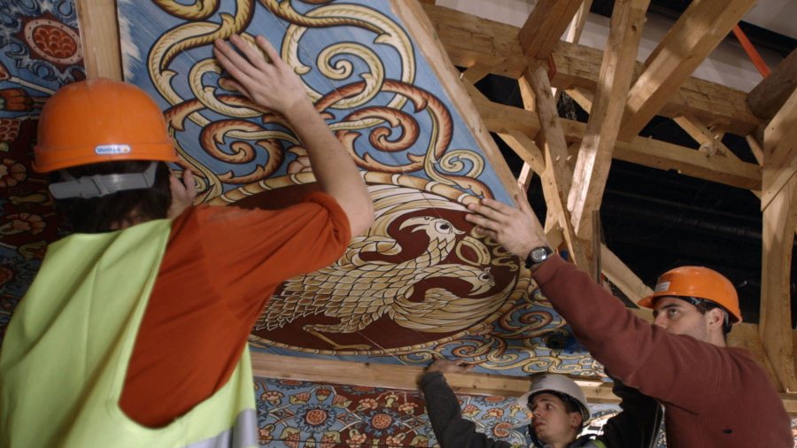 A construction crew places a painted ceiling panel into place in this scene from "Raise the Roof," a film about the reconstruction of a wooden 18th-century Polish wooden synagogue. (Trillium Studios)