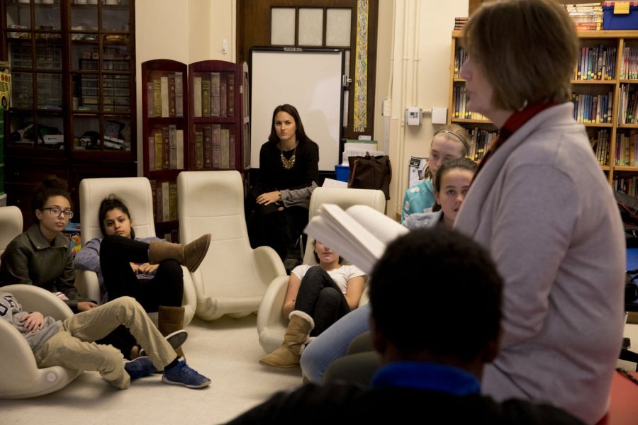 Elizabeth Erbafina '17, center, listens as Sue Weber '74 reads to a seventh-grade literacy class at Lewiston Middle School on March 2. Erbafina is student-teaching with Weber. (Phyllis Graber Jensen/Bates College)