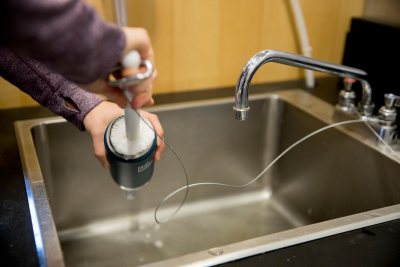 Laura Rand '18 demonstrates the new mug-washing station in Commons, which makes life more hygienic for folks toting their own mugs around -- as all Bates students on campus soon will be doing. (Phyllis Graber Jensen/Bates College)