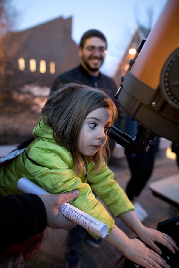 Isla Shea, 6, of East Auburn School, uses a telescope to view the moon as Evan Goldberg '19 looks on during the Astronomy Extravaganza on April 3. (Phyllis Graber Jensen/Bates College) 