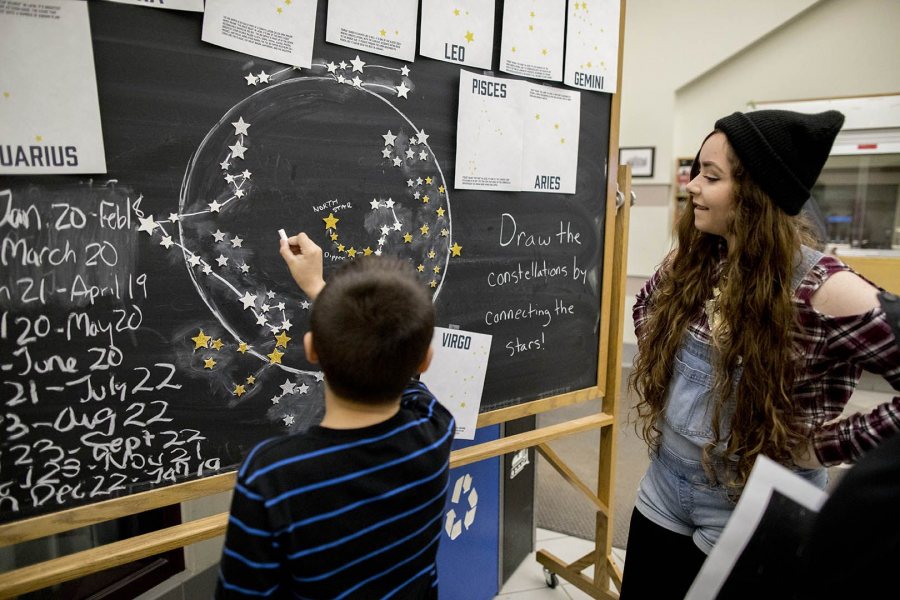 A boy works on the Connect the Constellations display as Emily Morse '17 of Machias, Maine, watches in Memorial Commons in Chase Hall. (Phyllis Graber Jensen/Bates College)