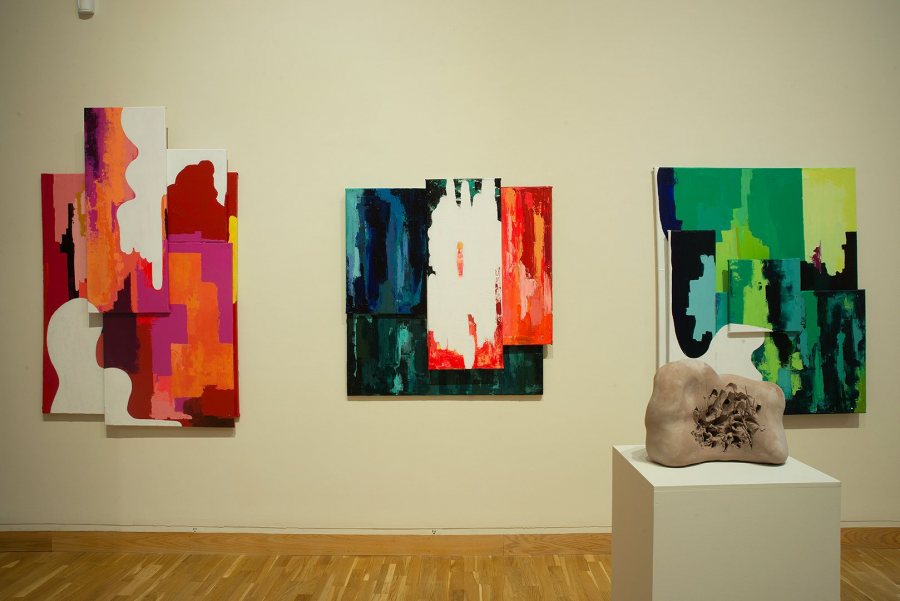 Three untitled paintings by Joanie Oates, with a sculpture by José Herrera in the foreground.