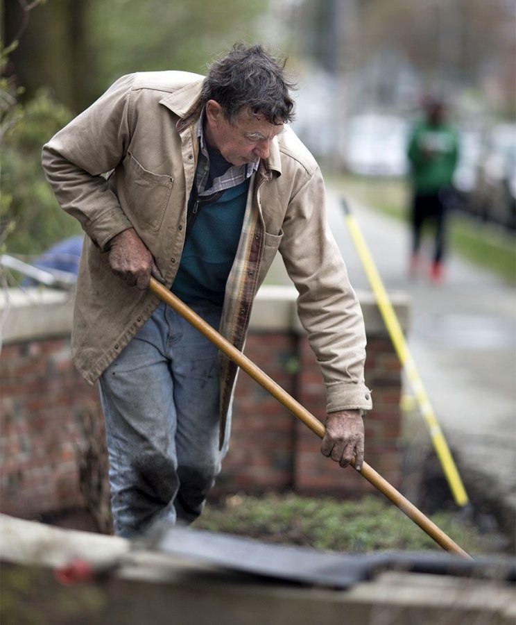 Bill Bergevin sweeps the sidewalk after a mulching session near Carnegie Science Hall. (Phyllis Graber Jensen/Bates College)