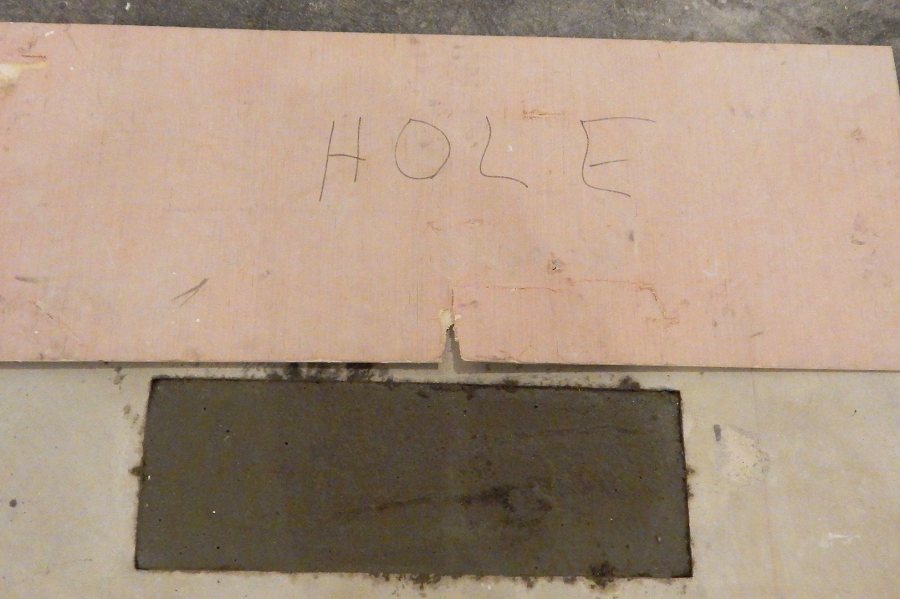 Fresh concrete plugs a disused HVAC opening in the subfloor of Carnegie 339. The sign covered the hole while the concrete was soft. (Doug Hubley/Bates College)