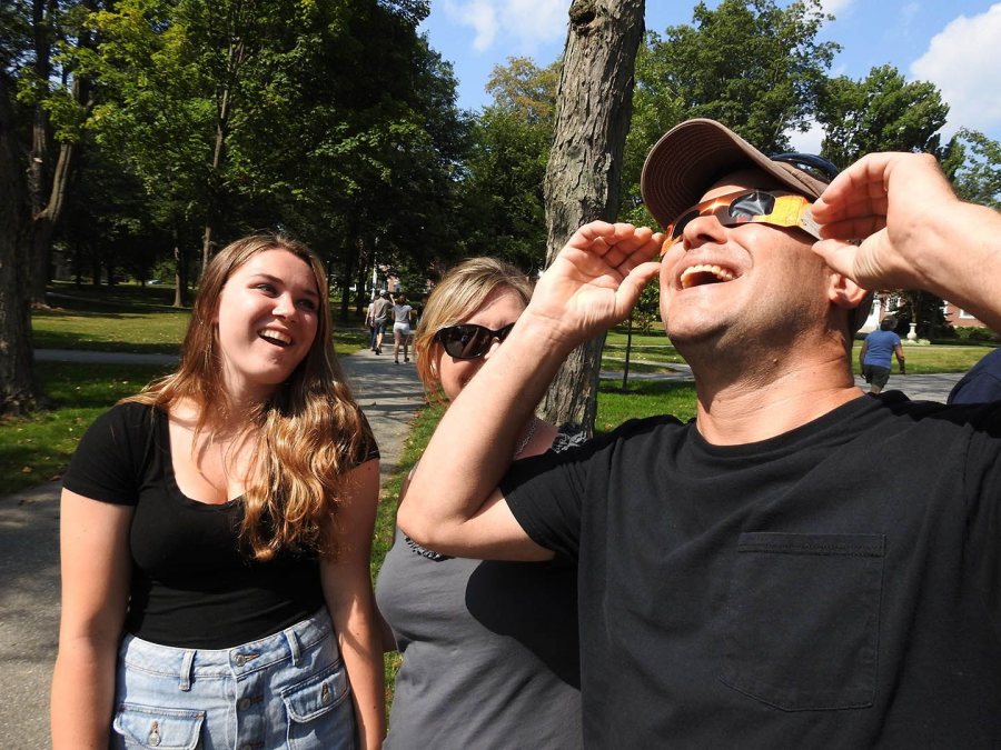 Pete Culcasi of Northbridge, Mass., looks at the eclipse through protective eyeglasses as his daughter, Maddie, and wife Jody, watch. A welder by trade, he'd also brought protective welder's glass. (Jay Burns/Bates College)