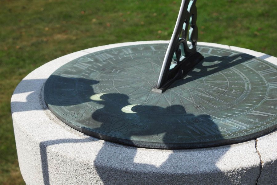 Fun with the sun: The partial eclipse is projected onto the Class of 1932 Sun Dial through a pair of binoculars. (Jay Burns/Bates College)