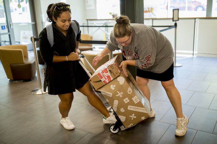 Retail Shipping and Parcel Clerk Laurie Grimmel helps Elizah Laurenceau '19 load recently-delivered packages onto a hand dolly on Oct. 10. (Phyllis Graber Jensen/Bates College)