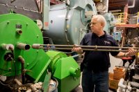 Darrel Scribner of Preferred Utilities Manufacturing Corp. starts the RFO burner on Tuesday by inserting what’s known as an ignition oil gun. (Phyllis Graber Jensen/Bates College)