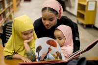 Rakiya Mohamed '18 of Auburn reads to her sisters Sareen Hassan (left) and Saheen Hassan (right) during the "Friends Across Difference Workshop" in Ladd Library. (Phyllis Graber Jensen)