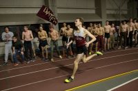 As teammates cheer him on, captain Rob Flynn ’18 runs the final leg of the famed 4x800 Blackout Relay at the Maine State Indoor Track and Field Championships in Merrill Gymnasium on Feb. 3. Run with lights dimmed, the Blackout Relay commemorates the 2001 race, when a storm caused a blackout during the race but the athletes kept going. (Phyllis Graber Jensen/Bates College)