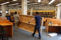 Weatherize Northeast carpenters carry a prefab temporary wall section into Ladd Library on April 18. The panel will be part of a barrier enclosing the construction of the new Accessible Education and Student Support Services center. (Doug Hubley/Bates College) 