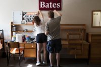 Abra Kaplan '21 of Oak Park, Ill., stretches to pin a Bates College banner on her wall with the assistance of her father Gary Kaplan while moving in to her new dorm at Rand Hall during move in day.
