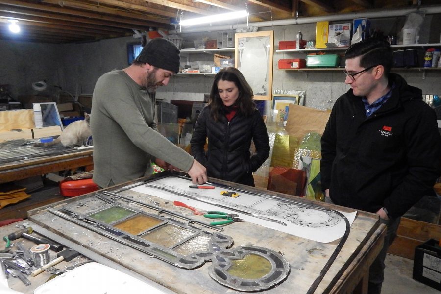 Stained-glass maker Nat Croteau of Phoenix Studio, at left, explains a point of technique to project managers Shelby Burgau of Bates and Dylan Poulin of Consigli Construction. (Doug Hubley/Bates College)