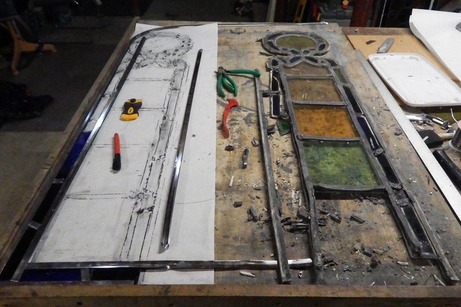 A partially dismantled stained-glass door insert at right, with materials for rebuilding it laid out at left. (Doug Hubley/Bates College)