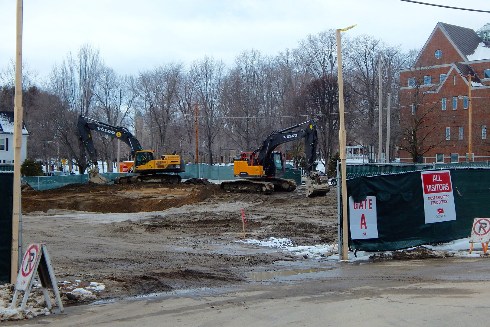 Seen through Gate A, opening onto Bardwell Street, two excavators rearrange the soil at the science building construction site. (Doug Hubley/Bates College)