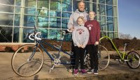 Chip Noble ’97 of Yarmouth, and daughter's  Abby, 10 and Emma, 7, pose for a portrait outside of Garmin's headquarters in Yarmouth on April 11, 2019.