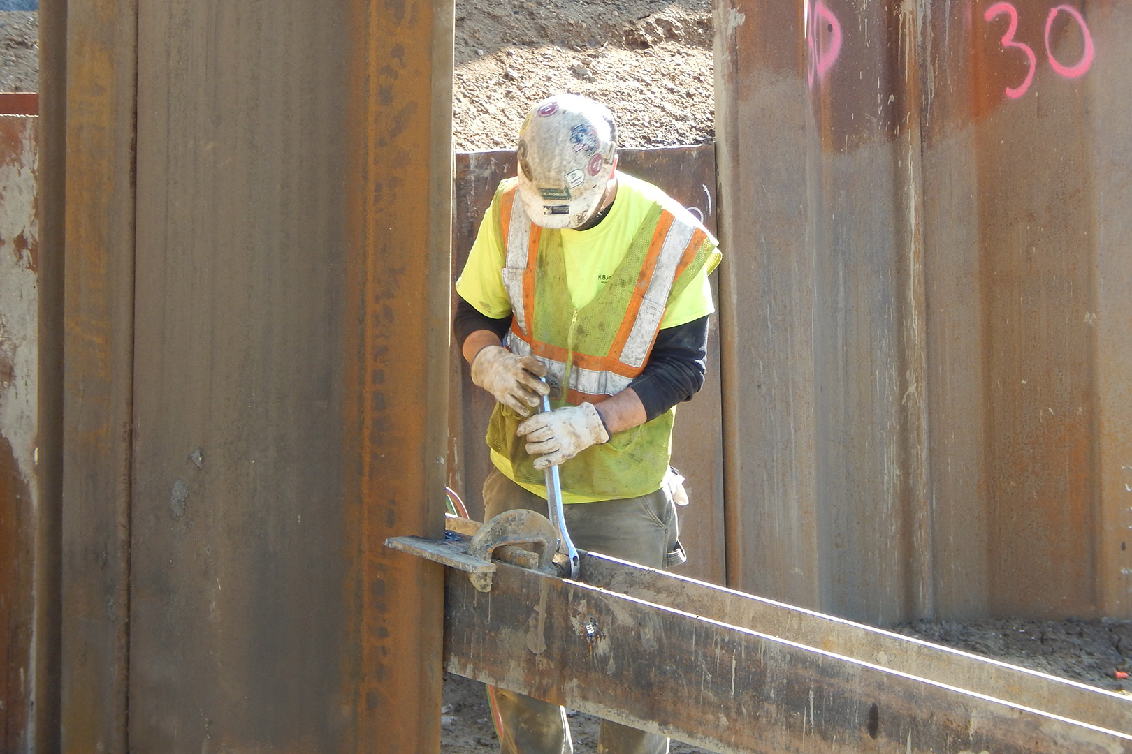 An employee of South Portland subcontractor H.B. Fleming tightens a clamp holding a sheet pile in place on May 6. (Doug Hubley/Bates College)