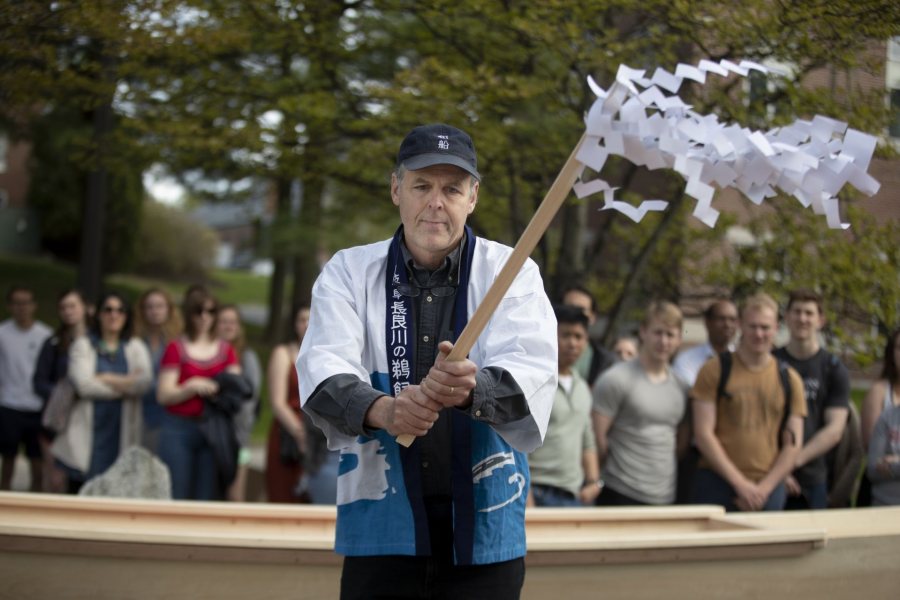 Douglas Brooks shakes the streamers over the boats. (Phyllis Graber Jensen/Bates College)