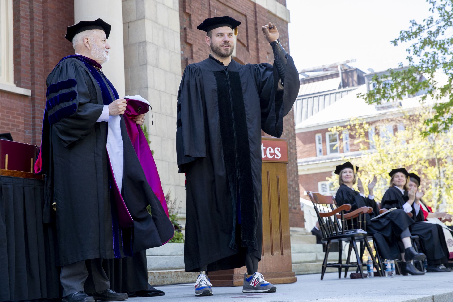 Travis Mills, a soldier injured in combat who is now an advocate for other combat veterans, receives an honorary Doctor of Humane Letters degree. Placing the collar on Mills is the college's mace bearer, Phillips Professor of Economics Michael Murray. (Phyllis Graber Jensen/Bates College)