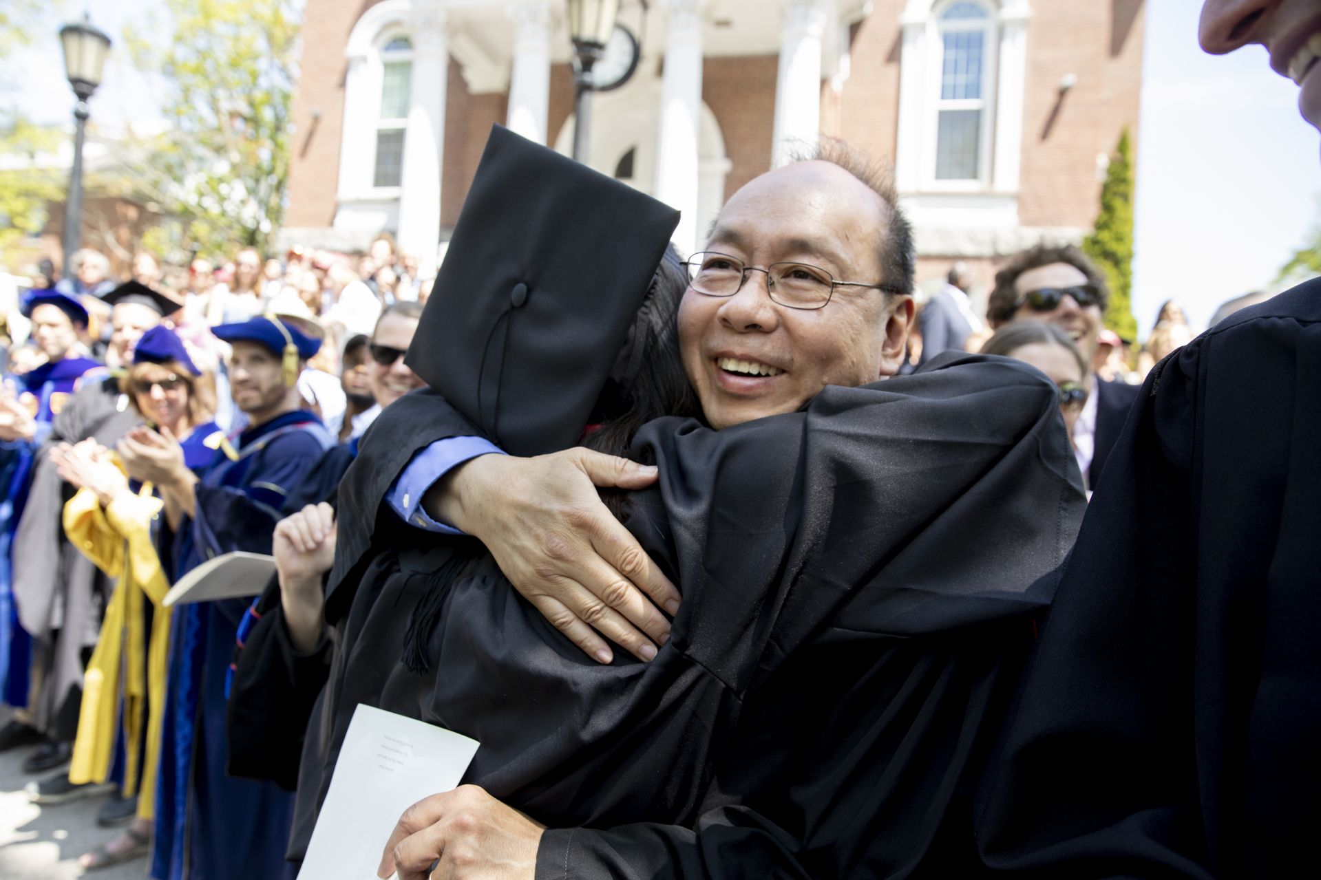 Math professor Peter Wong hugs a new graduate during the recessional. (Phyllis Graber Jensen/Bates College)