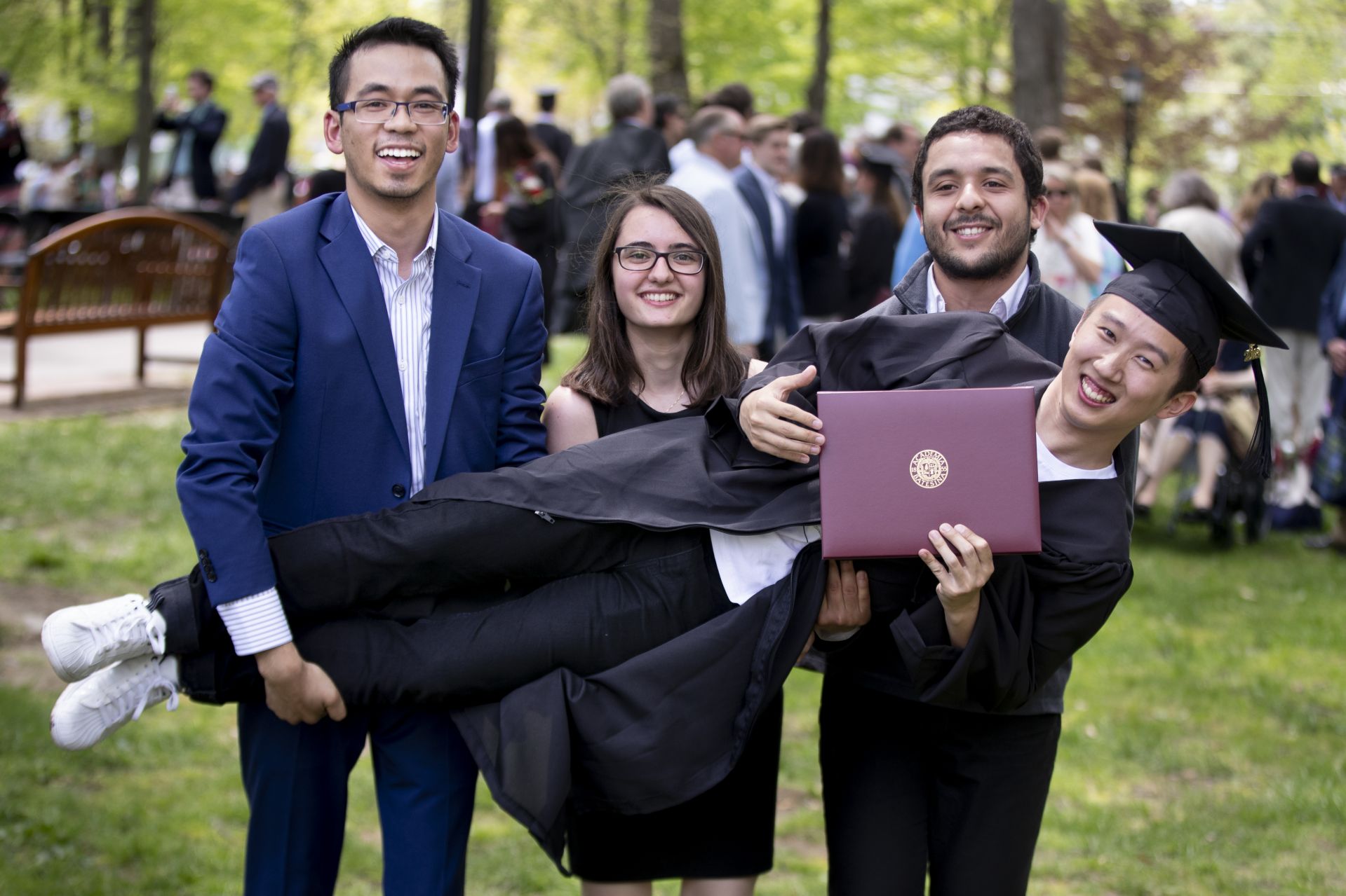 Max Huang '19, who graduated summa cum laude as a triple major in math, economics and physics, is held up by (from left) Deepsing Syangtan, Maria-Anna Chrysovergi, and Salim Ourari, all ’18. (Phyllis Graber Jensen/Bates College) 