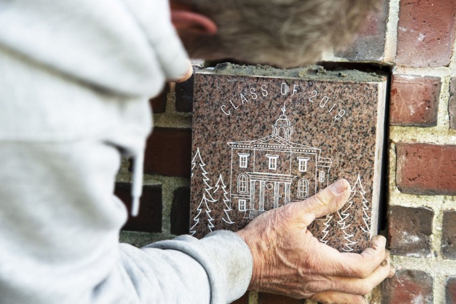 Ronald "Ron" Tardif, a facility services mason with the Cutten Maintenance Center at Bates College, places the 'Class of 2018' ivy stone near the entrance of Pettengill Hall on May 22, 2019.