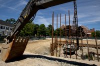 Framed by the arm of an excavator, pipe piles stand tall in the Bonney Science Center foundation hole on June 24, 2019. (Phyllis Graber Jensen/Bates College)