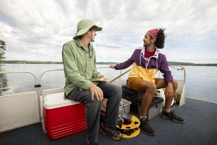 Topher Castaneda ’20 (right) sits on a boat with Holly Ewing, Christian A. Johnson Professor of Interdisciplinary Studies, as they do fieldwork on Lake Auburn. (Phyllis Graber Jensen/Bates College)