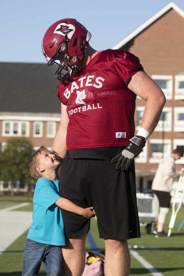 Captain CourageousSix-year-old Brayden Austin gives a leg hug to Phil Simplicio ’20 of West Hartford, Conn., during a football practice at Garcelon Field in September. 