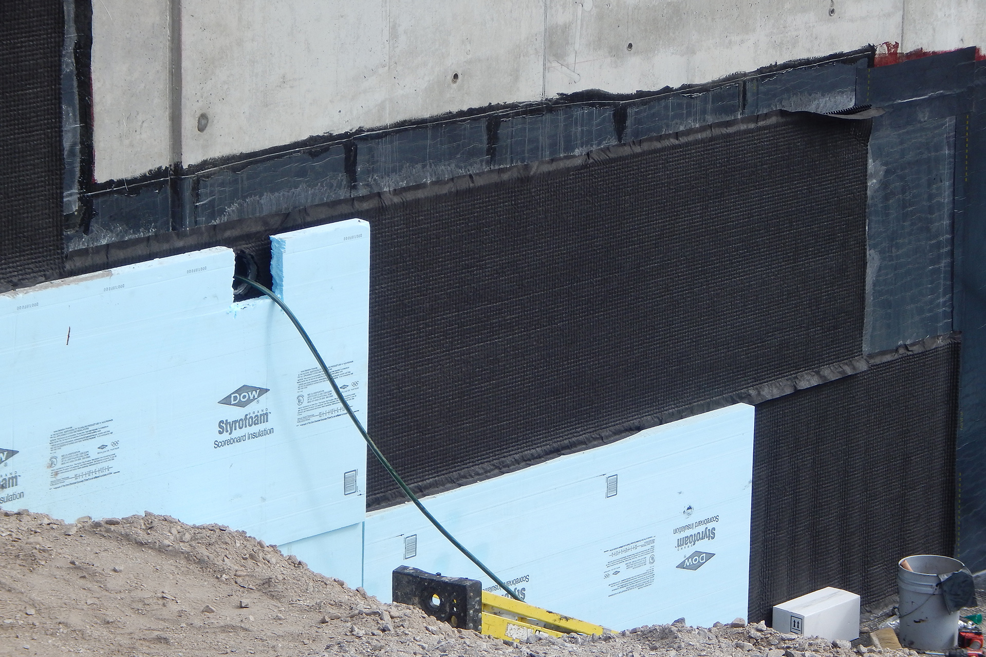 Here's a section of the Bonney Science Center foundation wall showing blue thermal insulation panels, black waterproofing board and waterproofing film, and, at upper right, just a bit of the maroon adhesive that holds the film in place. (Doug Hubley/Bates College)