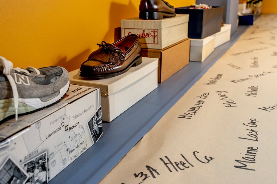 Brand and business names associated with the local shoe industry are handwritten on a long strip of paper, displayed with some of the shoes named. (Phyllis Graber Jensen/Bates College)