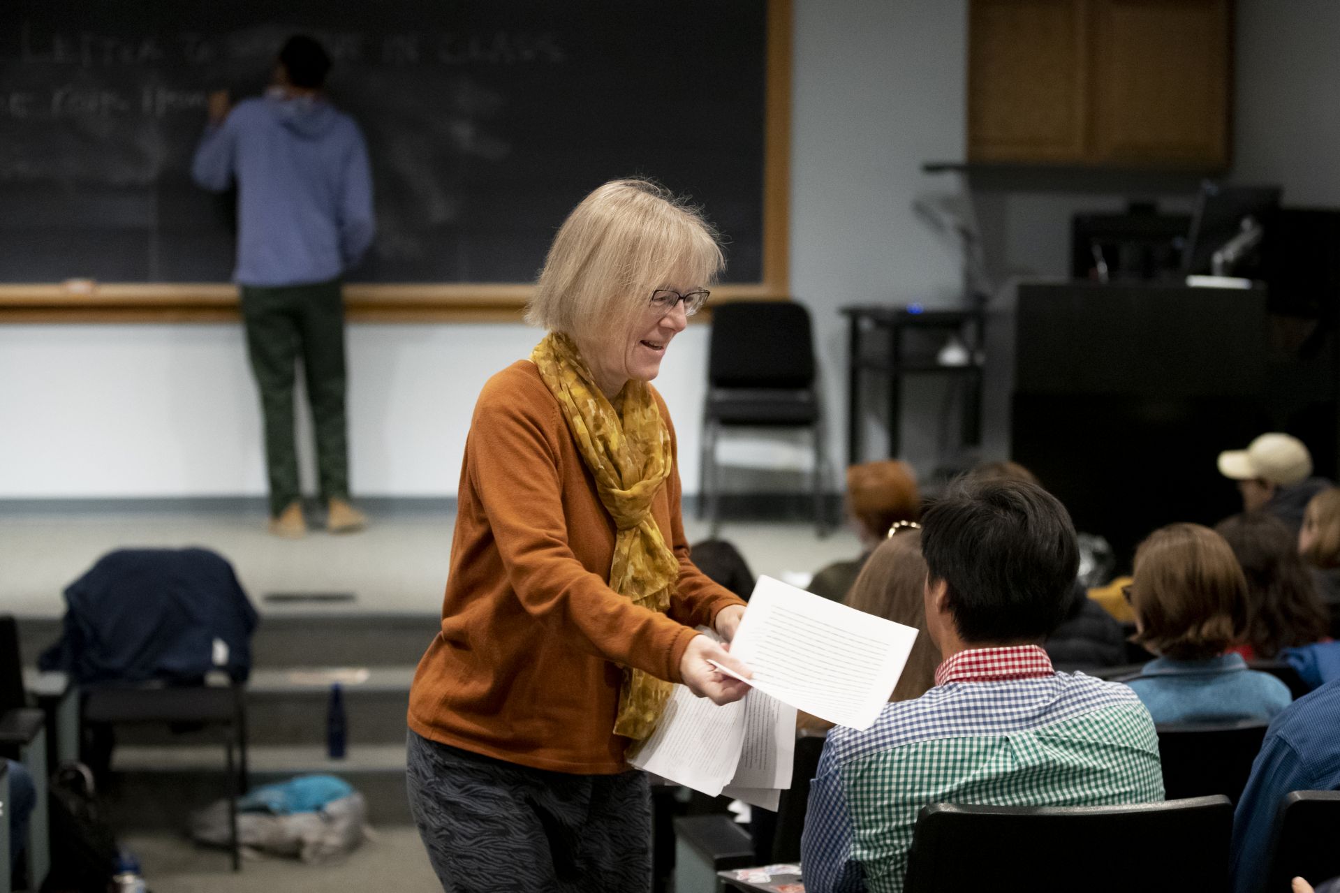 As the 2019 Otis Lecturer Ross Gay puts a writing prompt on the blackboard, Costlow hands back papers to her students. (Phyllis Graber Jensen/Bates College)