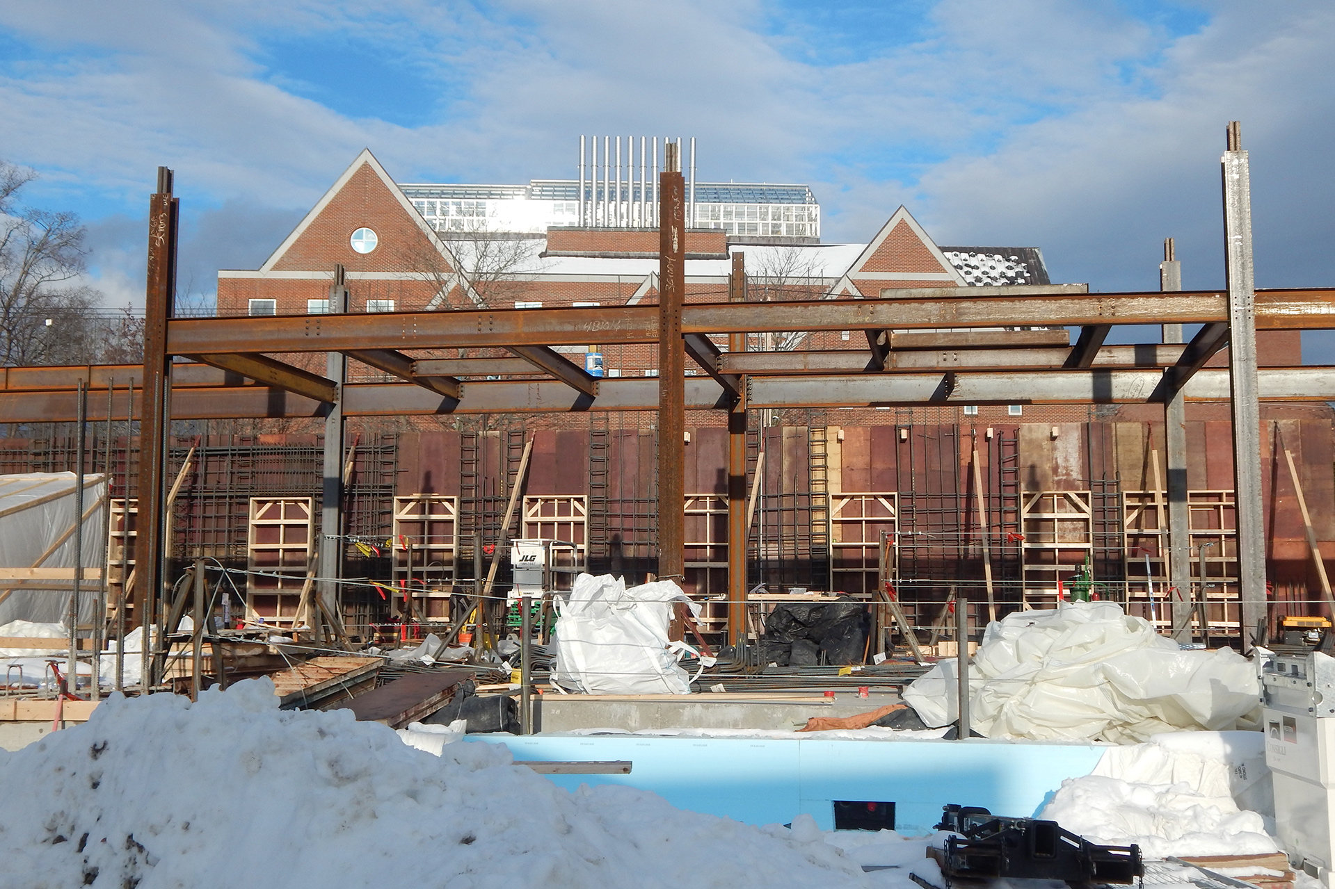 The state of things at the Bonney Science Center in early December 2019. In the background is a wall of concrete forms hung with rebar and window knockouts. Structural steel dominates the image. Showing at the bottom is blue insulation protecting the foundation wall. (Doug Hubley/Bates College)