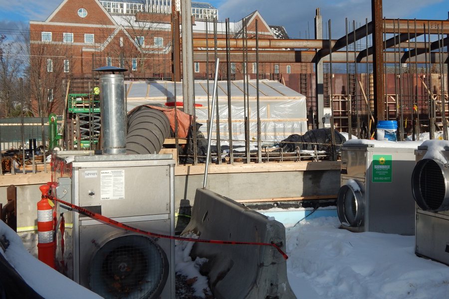 Three space heaters at the science building. The one at left is in service, pumping heat into the basement through a flexible duct and the plastic-shrouded headhouse. (Doug Hubley/Bates College)