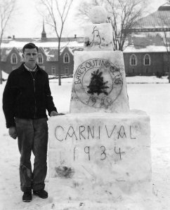 In 1934, a student stands next to a Bates Outing Club snow sculpture featuring the BOC logo. (Muskie Archives and Special Collections Library)
